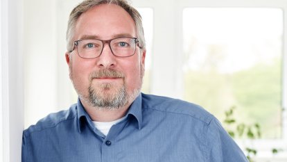 Porträt von Stephan Klein, Head of Customs & Export Service, lächelnd in einem blauen Hemd vor einem hellen Hintergrund.